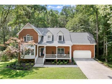 Traditional brick home with a manicured front yard, a covered porch, and an attached garage at 4392 Windsor Oaks Cir, Marietta, GA 30066