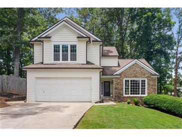 Charming home featuring a two-car garage, stone accents, and lush landscaping at 4816 Morning Chase Nw, Acworth, GA 30102