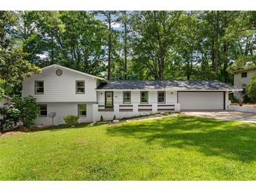 Charming two-story home with a well-manicured lawn, complemented by mature trees and a fresh, white facade at 4214 Williamsburg Dr, College Park, GA 30337