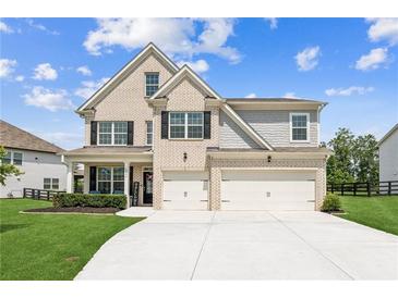 Beautiful two-story home featuring a two-car garage, brick facade, and a well-manicured front lawn at 6825 Rambling Vale, Cumming, GA 30028