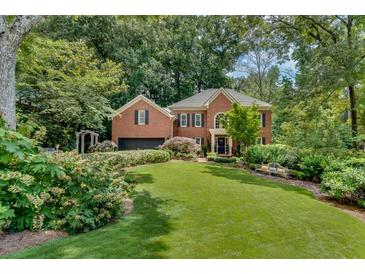 Charming brick home with lush landscaping, a well-manicured lawn, and mature trees at 1676 Grove Park Way, Decatur, GA 30033