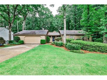 Charming single-story home with a lush green lawn, mature trees, and a two-car garage at 2528 Chimney Springs Dr, Marietta, GA 30062
