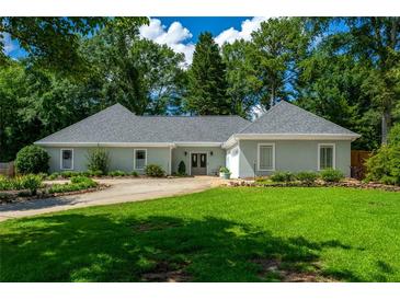Charming one-story home with a well-manicured lawn, circular driveway, and lush landscaping at 4016 Dover Ave, Alpharetta, GA 30009