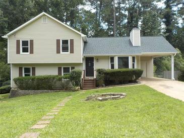 Charming two-story home features a well-maintained lawn, brick path, and a convenient carport for covered parking at 1380 Ashbrook Dr, Lawrenceville, GA 30043