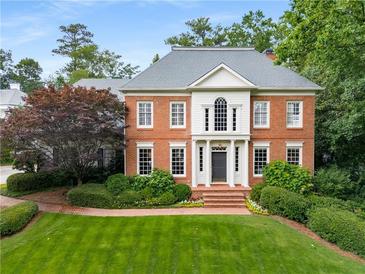 Charming brick home featuring manicured lawn and lush landscaping, offering timeless curb appeal at 2878 Wesley Heath Nw, Atlanta, GA 30327