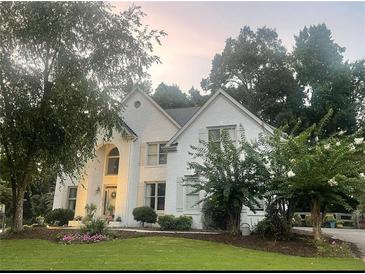 Charming, white two-story home with manicured lawn and mature trees at 7235 Compton Cir, Cumming, GA 30040