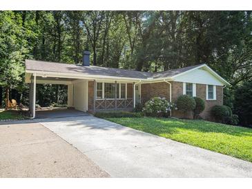 Charming brick home with a spacious carport and well-maintained front yard landscaping at 3390 Kenland Se Rd, Smyrna, GA 30082