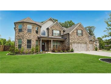Beautiful two-story brick home with well-manicured lawn and attached two-car garage at 5381 Front Runner Ct, Sugar Hill, GA 30518