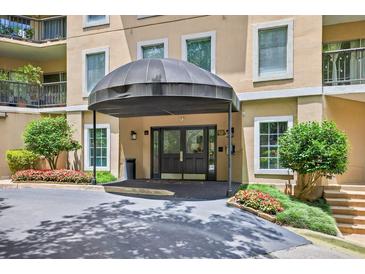 Covered entrance of building featuring glass double doors, manicured shrubs and beautiful red flowers at 1 Biscayne Nw Dr # 112, Atlanta, GA 30309