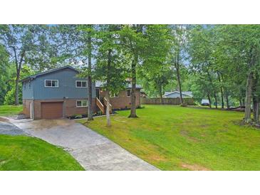 Two-story home with a gray exterior, brick accents, attached garage, a long driveway and a spacious front yard at 1031 Washington Ave, Woodstock, GA 30188