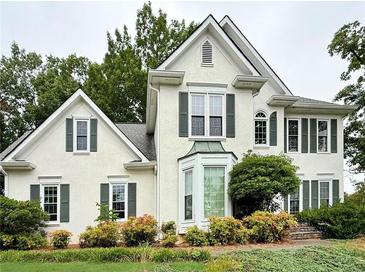 Charming two-story house with stucco siding, a manicured lawn, and lush landscaping at 4715 Scotney Ct, Suwanee, GA 30024