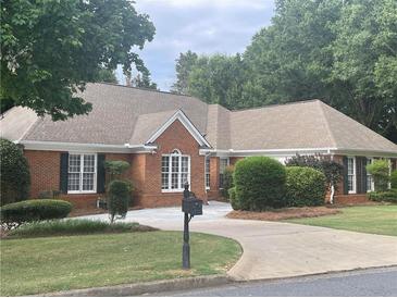 Charming one-story brick home with a well-maintained lawn, mature trees, and traditional architectural details at 5005 Johns Creek Ct, Alpharetta, GA 30022