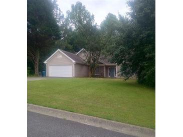 Charming single-story home features a spacious front yard, attached two-car garage, and traditional architectural details at 2868 Evonshire Ln, Dacula, GA 30019