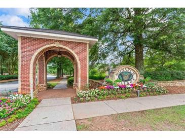 Charming brick entrance to the Monarch Village neighborhood with colorful flower beds and mature trees at 615 Brookwater Dr, Stockbridge, GA 30281