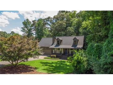 Charming Cape Cod-style home with a manicured lawn and mature trees at 1066 Sea Oats Sw Way, Lilburn, GA 30047