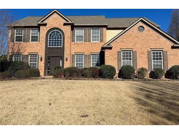 Charming two-story brick home featuring a landscaped front yard, traditional shutters, and a grand arched entryway at 1085 Blackwood Ct, Suwanee, GA 30024