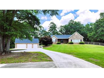 Charming stone home with a well-manicured lawn, long driveway, and detached garage at 5300 Haynes Creek Dr, Loganville, GA 30052