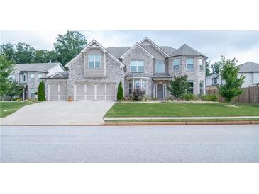 Stunning two-story home with a three-car garage, stone and siding details, and a well-manicured lawn at 3739 In Bloom Way, Auburn, GA 30011