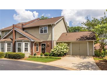 Charming two-story townhome featuring a brick facade, attached garage, and well-maintained landscaping at 104 Powell Cv, Decatur, GA 30030