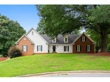Charming two-story home with a well-manicured front yard, brick accents, and mature trees at 1732 Winding Woods Ln, Jonesboro, GA 30236