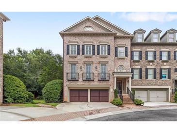 Beautiful brick townhome featuring a two-car garage, black shutters, and manicured landscaping at 2291 Falmouth Se Ct # 23, Smyrna, GA 30080