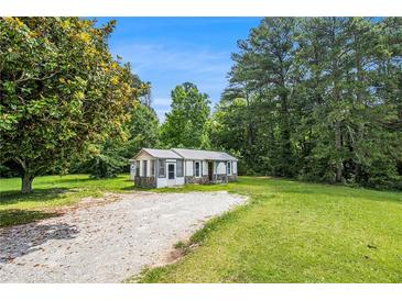 View of cozy home on large lot with gravel driveway and lush green lawn at 1186 Eastview Ne Rd, Conyers, GA 30012