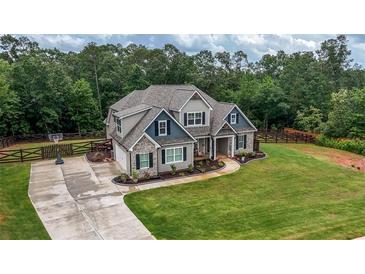 Charming two-story home with a lush green lawn, fenced yard, and long concrete driveway at 7532 Milford Pl, Douglasville, GA 30135
