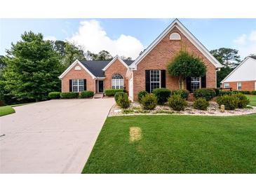 Charming brick home with a well-manicured lawn, complemented by mature trees and a paved driveway at 7090 Valley Landing Ct, Cumming, GA 30041