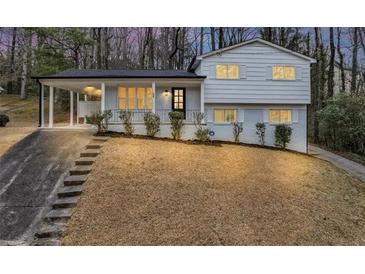 Charming two-story home featuring a light-colored exterior with a covered porch and a beautifully landscaped front yard at 847 Magna Carta Nw Dr, Atlanta, GA 30318