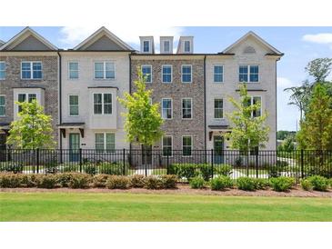 Attractive townhome exterior with white-painted brick, black fence and well-manicured landscaping at 102 Brackley Dr, Cumming, GA 30040