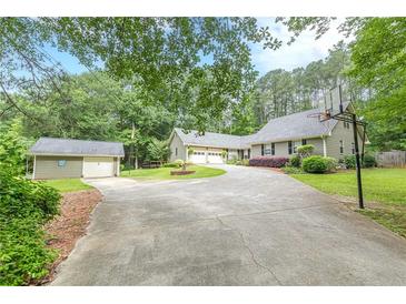 Charming home featuring a lush lawn, long driveway, and detached garage for convenience and curb appeal at 1667 Quail Run, Conyers, GA 30094