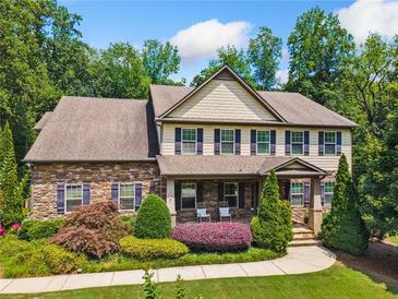 Charming two-story home featuring a stone facade, landscaped yard, and inviting front porch with rocking chairs at 1344 Hamilton Creek Nw Dr, Kennesaw, GA 30152
