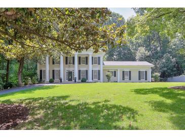 Stately two-story home with columns, black shutters, green lawn, and mature shade trees at 575 Valley Hall Dr, Sandy Springs, GA 30350