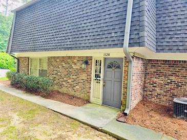 Charming brick townhome featuring a gray front door and well-maintained landscaping at 1128 Hampton Way, Atlanta, GA 30324