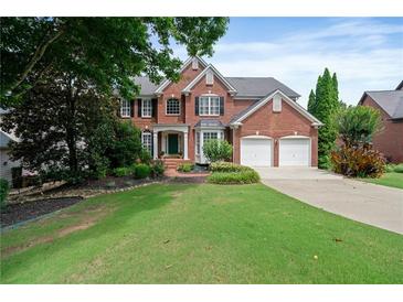 Charming two-story red brick home with lush green lawn, mature trees, and a two-car garage at 1775 Porterton Way, Cumming, GA 30041