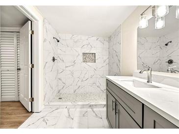 Modern bathroom with a large walk-in shower with white marble tile and gray vanity at 2331 Luther St, Lithonia, GA 30058
