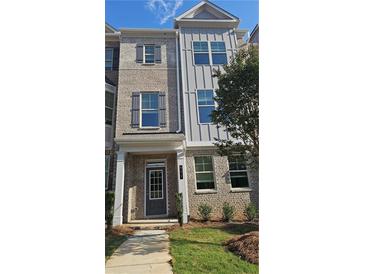 Charming townhome featuring a brick facade, gray accents, and manicured landscaping at 545 Fundao Ln # 25, Lawrenceville, GA 30046