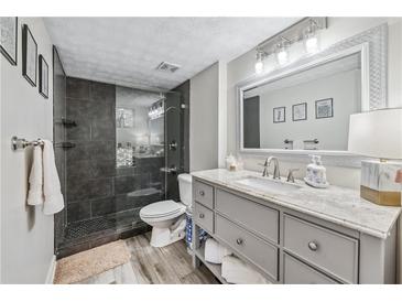 Modern bathroom featuring a glass-enclosed shower, gray vanity with granite countertop, and wood-look flooring at 3115 Seven Pines Ct # 308, Atlanta, GA 30339