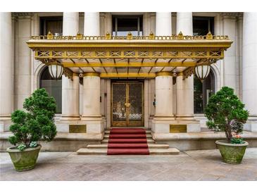 Grand building entrance with gold awning, columns, red carpet, and potted trees at 75 Ponce De Leon Ne Ave # 1006, Atlanta, GA 30308