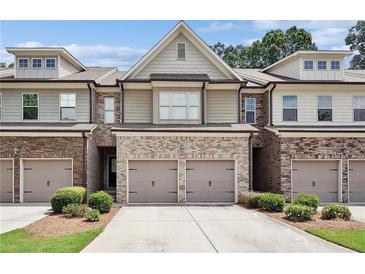 Charming townhome with brick and stone accents, a two-car garage, and well-maintained landscaping at 5590 Bright Cross Way, Suwanee, GA 30024