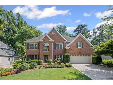 Charming brick home with a manicured lawn, colorful flowerbeds, and an attached two-car garage at 3675 Ridgeway Ter, Suwanee, GA 30024