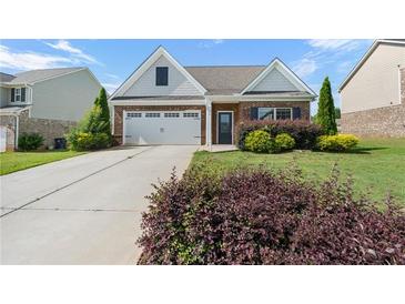 Charming brick home featuring an attached two-car garage, landscaped yard, and manicured lawn at 196 Al Jennah Blvd, Locust Grove, GA 30248