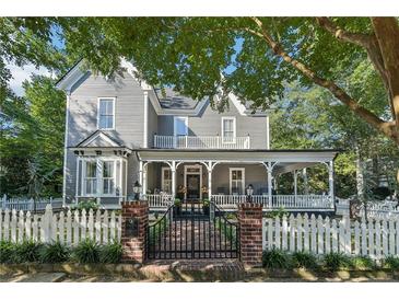Charming two-story home featuring a covered front porch and a white picket fence at 207 E Hightower E Trl, Social Circle, GA 30025