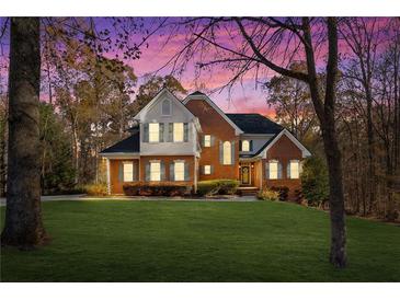 Charming two-story brick home with lush lawn, mature trees and colorful sunset sky at 340 Antebellum Way, Fayetteville, GA 30215