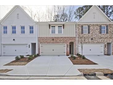 Charming townhomes showcasing brick and siding exteriors, each with a one-car garage at 693 Sunstone Ln, Lawrenceville, GA 30043