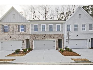 New townhome construction with brick and painted exteriors, garages and sidewalks at 697 Sunstone Ln, Lawrenceville, GA 30043
