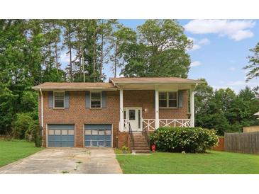 Charming brick home featuring a covered front porch, an attached two-car garage, and a well-manicured lawn at 115 Elizabeth Way, Ellenwood, GA 30294