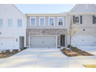 New townhome features a brick facade, attached garage, and landscaping at 905 Agate Ln, Lawrenceville, GA 30043