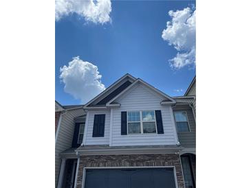 Stylish two-story home featuring stone accents, black shutters, and a gray garage door, all under a beautiful blue sky at 5715 Radford Loop # 15, Fairburn, GA 30213