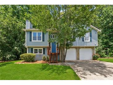 Charming two-story home featuring a blue exterior, landscaped yard, and two-car garage at 3450 Saddleton Way, Douglasville, GA 30134